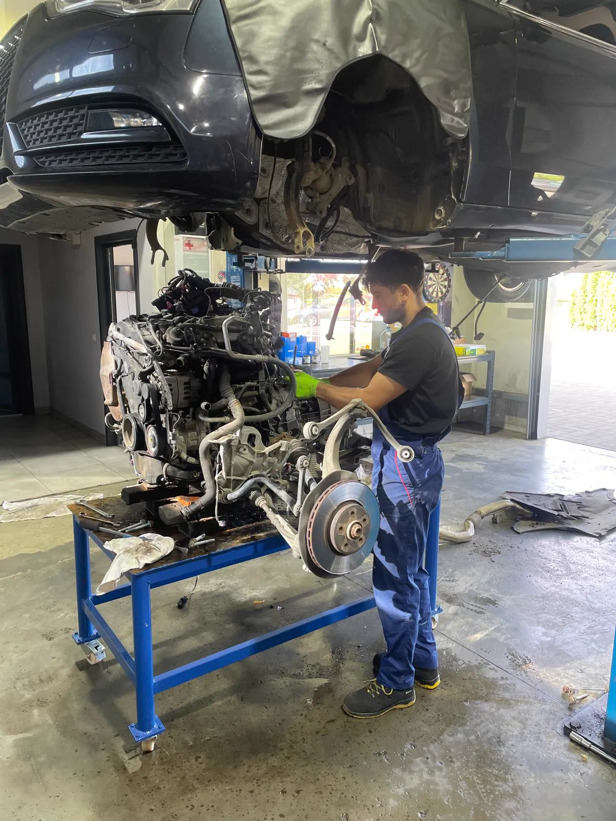 Mecanic lucrând la un motor cu suspensia, așezat pe masa de lucru