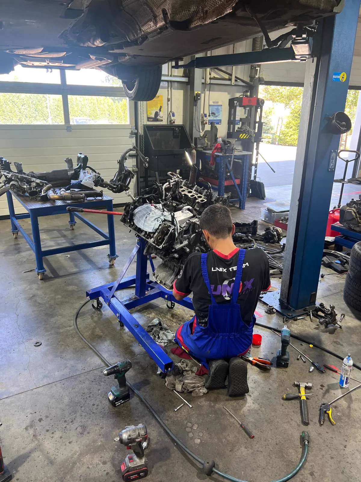 Mecanic lucrând la un motor montat pe stand, în atelier